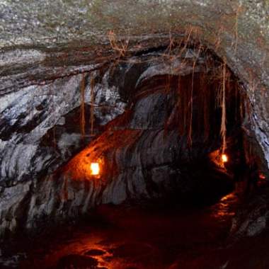 Dimly lit rocky tunnel with two lanterns hanging.