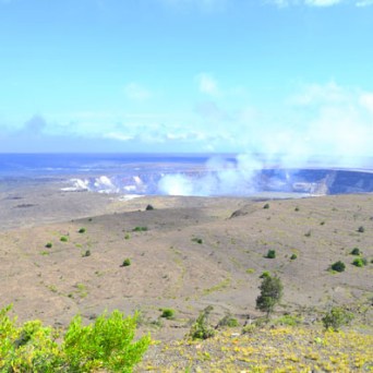 Volcanic crater with smoke under a blue sky in a barren landscape.