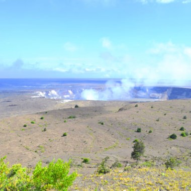 Volcanic crater with smoke under a blue sky in a barren landscape.